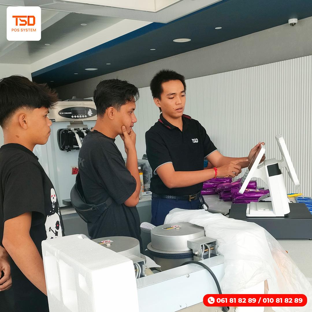 KHQR POS Cambodia — ទូទាត់ ABA & KHQR ផ្ទាល់ពីម៉ាស៊ីនគិតលុយ 14 KHQR POS Cambodia — TSD staff demonstrating white POS terminal